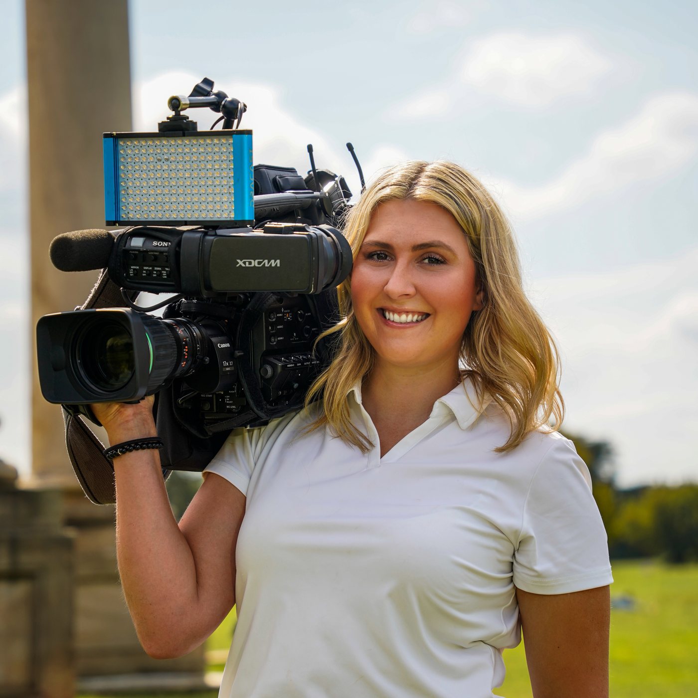 Kimi Fleming smiling, with a broadcast news camera on her shoulder